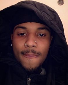 a man with piercings on his nose wearing a hoodie and looking at the camera