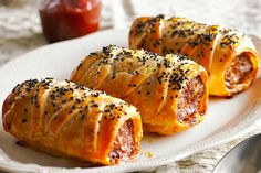 three pastries on a white plate with pepperoni and black sesame sprinkles