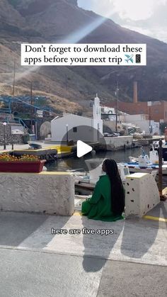 a woman sitting on the edge of a pier next to boats