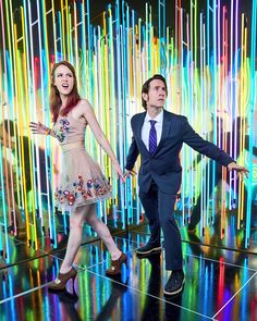 the man and woman are dancing in front of colorful lines on the wall behind them