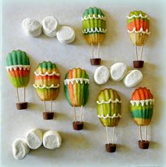 there are many colorful hot air balloons on the table with marshmallows in them