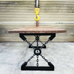 a wooden table with chains on it and a yellow light hanging from the top, in front of a garage door