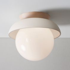 a white light hanging from the ceiling with a wooden fixture on it's side