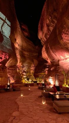 an outdoor seating area with candles lit up in front of large rock formations at night