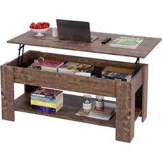 a wooden table topped with a laptop computer next to a shelf filled with books and magazines