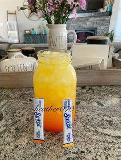 two candy bars sitting on top of a table next to a jar filled with orange juice