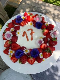 a cake with strawberries and daisies on it is sitting on a table outside