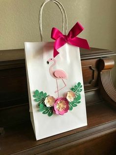 a paper bag with a pink flamingo and flowers on it sitting on a piano