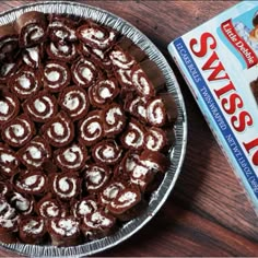 a box of swiss roll cake next to a pie tin on a wooden table top