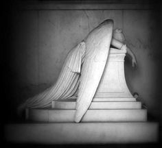 an angel statue sitting on top of a white marble pedestal with its wings spread out