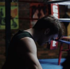 a man standing in a boxing ring with his hand on the ground and looking down