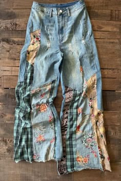 an old pair of jeans with patches and flowers on them sitting on a wooden floor