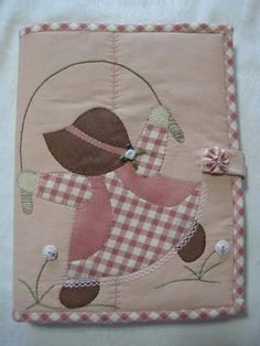 a pink and white patchwork quilt with a girl on it's back holding a flower