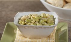 a white bowl filled with food sitting on top of a green place mat next to a bowl of cookies