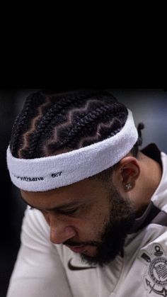 a man with dreadlocks and a white headband is looking at his cell phone