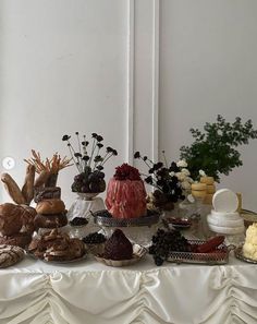 a table topped with cakes and pastries on top of a white cloth covered table