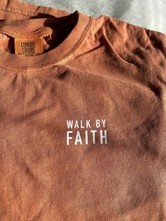 an orange shirt with the words walk by faith on it