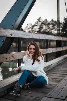 a woman is sitting on a bridge and smiling