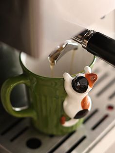 a coffee cup being filled with liquid from a espresso machine that is pouring milk into it