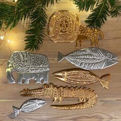 five metal fish and alligator ornaments hanging from a christmas tree