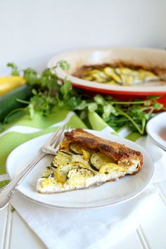 a slice of quiche on a plate with a fork and knife next to it