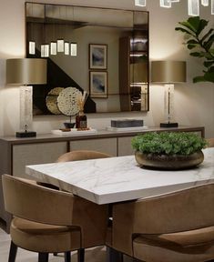 a dining room table with chairs and a vase on it in front of a mirror