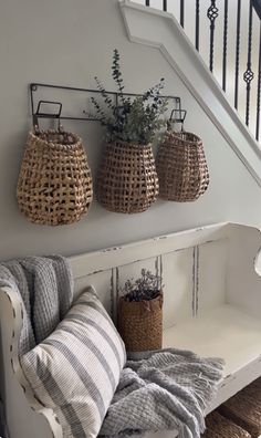 three baskets are hanging on the wall above a bench with two pillows and a pillow