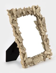 an ornate gold leafy mirror on a black stand