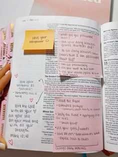 an open book with sticky notes attached to it and someone's hand holding one