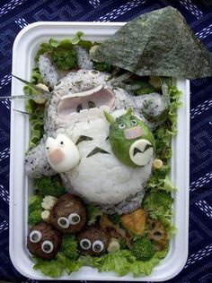 a plastic container filled with food covered in fake animals and veggies on top of it