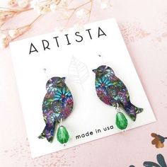 a pair of bird shaped earrings on top of a card