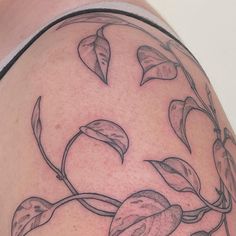 a tattoo on the back of a woman's shoulder with leaves growing out of it