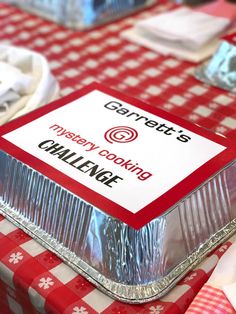 a red and white checkered table cloth with a tin container on it that says gannett's merry cooking challenge