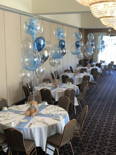 a room filled with tables covered in blue and silver balloons