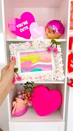 someone is holding up a valentine's day card in front of a bookcase