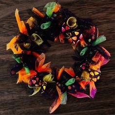 a close up of a wreath on a wooden surface with butterflies and leaves painted on it