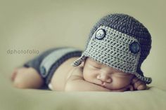 a baby wearing a crocheted hat laying on top of a bed