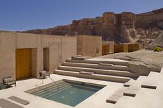 an outdoor swimming pool with steps leading up to it and mountains in the background on a sunny day