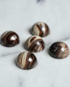 marbles are arranged on a white surface with black and brown swirls in the middle