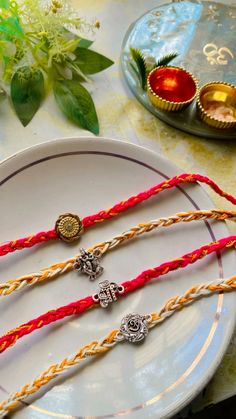 three braided bracelets sitting on top of a white plate next to some flowers