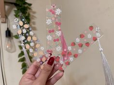 a person holding up some stickers with flowers and berries on them in front of a plant