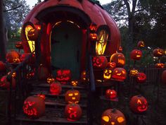 many pumpkins are lit up in front of a house with carved faces on it