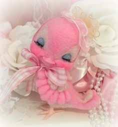 a pink stuffed animal sitting on top of a table next to white flowers and pearls