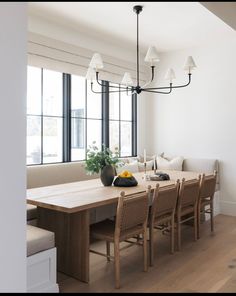 a dining room table and chairs in front of large windows