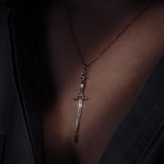 a woman wearing a necklace with a cross hanging from it's side, in the dark