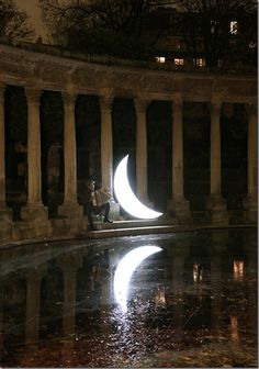 a person sitting on the ground next to a pool with a half moon in it