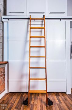 a ladder leaning against the wall in front of a white closet with wooden flooring