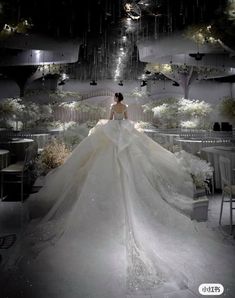 a woman in a white wedding dress is walking through the room with chandeliers hanging from the ceiling