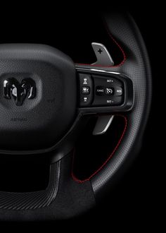 the interior of a car with red stitchs and steering wheel controls on black background