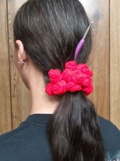 a woman with long black hair wearing a red crochet flower in her ponytail